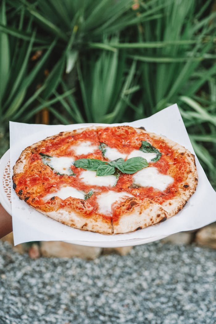 A mouth-watering Margherita pizza topped with fresh basil, captured outdoors during the day.